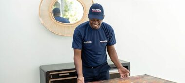 Professional art mover carefully packing a framed painting using protective materials to ensure safe transport during a local or international move.