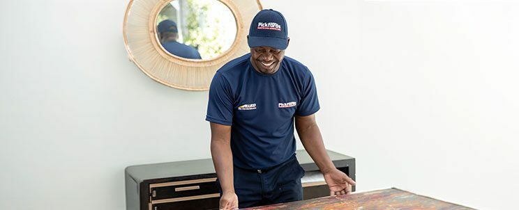 Professional art mover carefully packing a framed painting using protective materials to ensure safe transport during a local or international move.