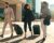 Three business professionals walking with suitcases through a modern business district during a corporate relocation.